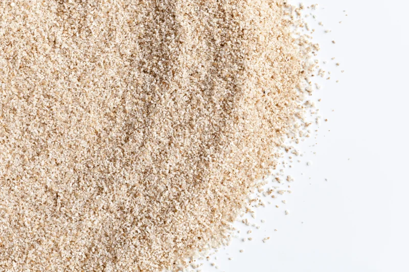 Fine dry beach sand scattered across the upper-left corner of a white surface