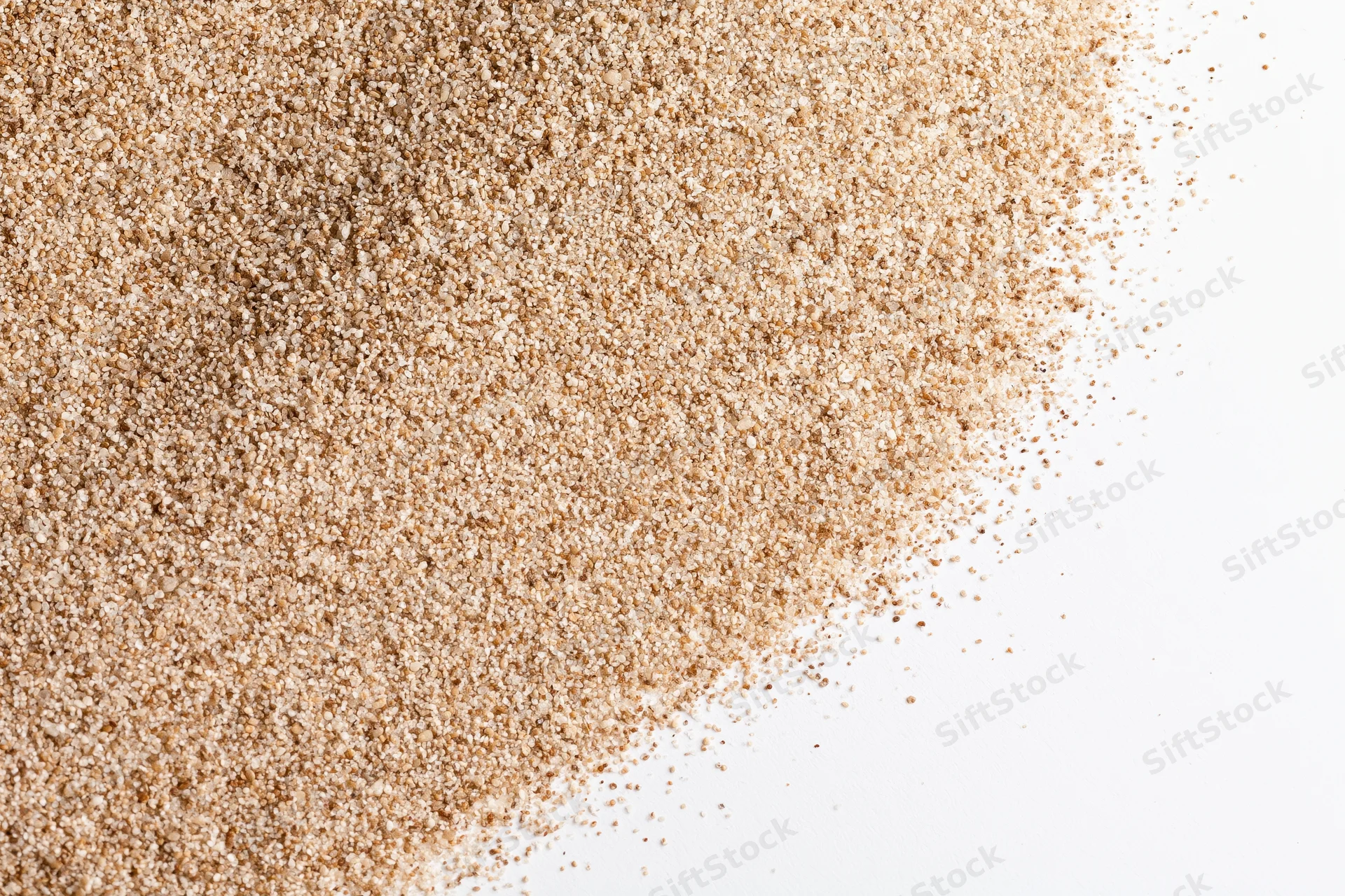 Fine dry beach sand scattered across the upper-left corner of a white surface
