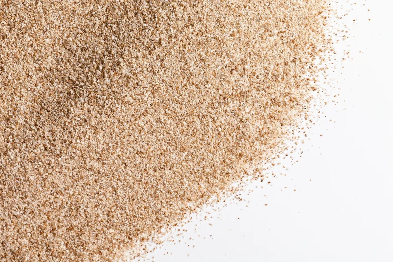 Fine dry beach sand scattered across the upper-left corner of a white surface