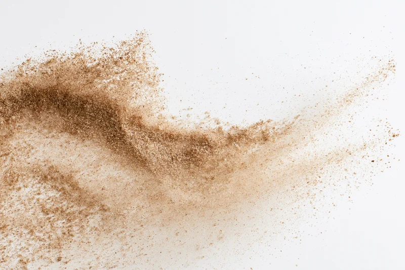 Fine brown sand exploding mid-air in frozen motion against white background