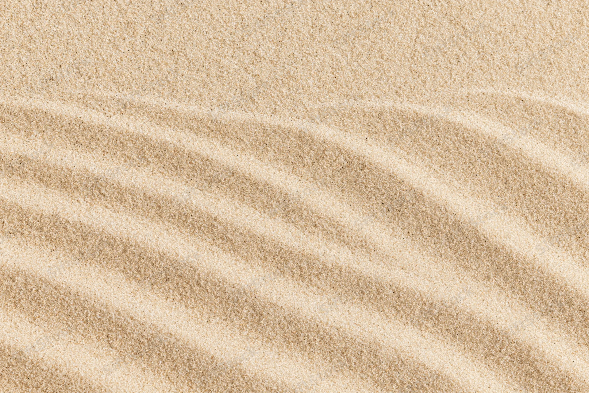Close-up of rippled sand surface with parallel wave patterns