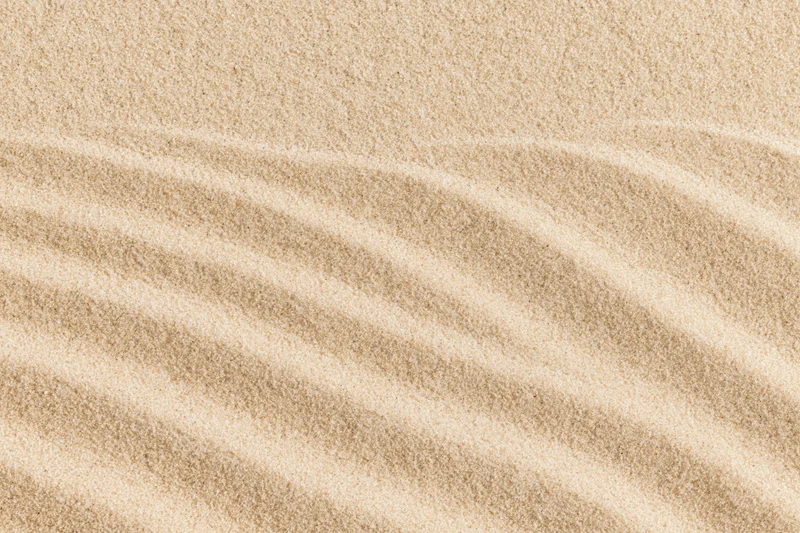Close-up of rippled sand surface with parallel wave patterns