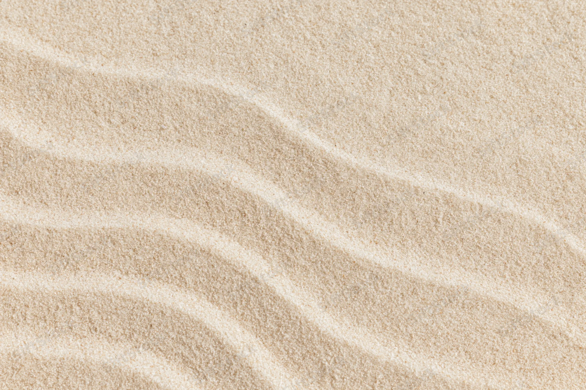 Closeup of fine sand surface with parallel ripples forming a smooth natural pattern