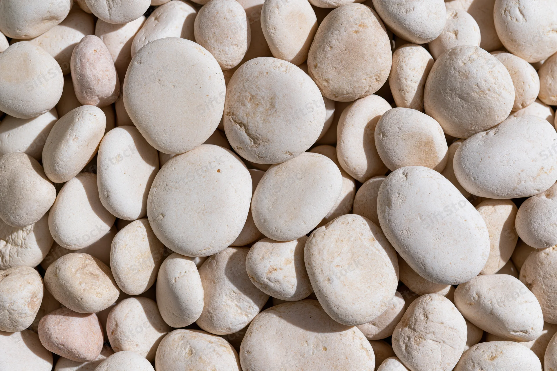 Smooth rounded white pebbles arranged in a flat lay covering the entire frame
