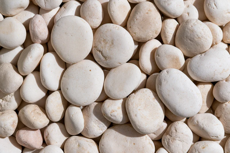 Smooth rounded white pebbles arranged in a flat lay covering the entire frame