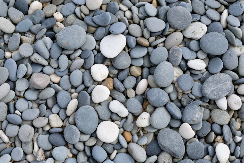 Smooth rounded pebbles scattered across a beach surface in an overhead flat lay view
