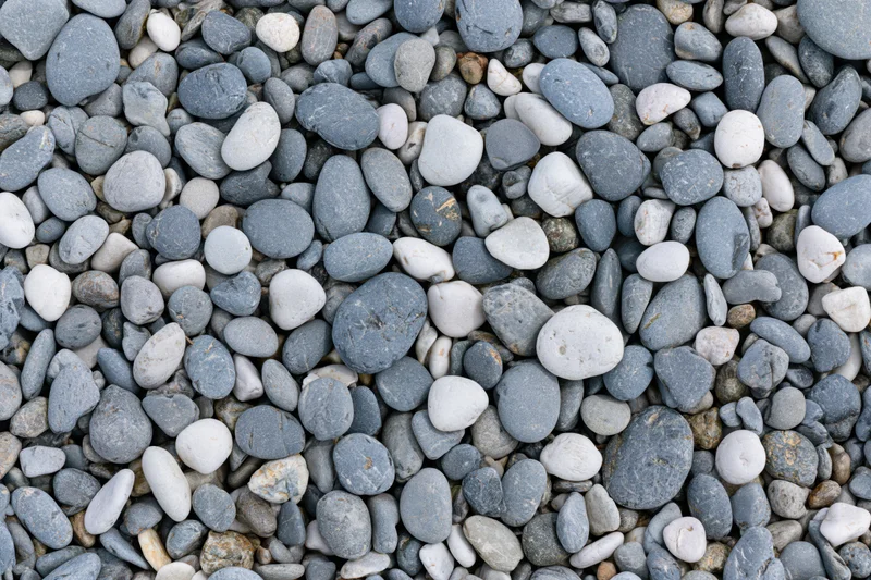 Smooth rounded pebbles scattered across a beach surface in an overhead flat lay view