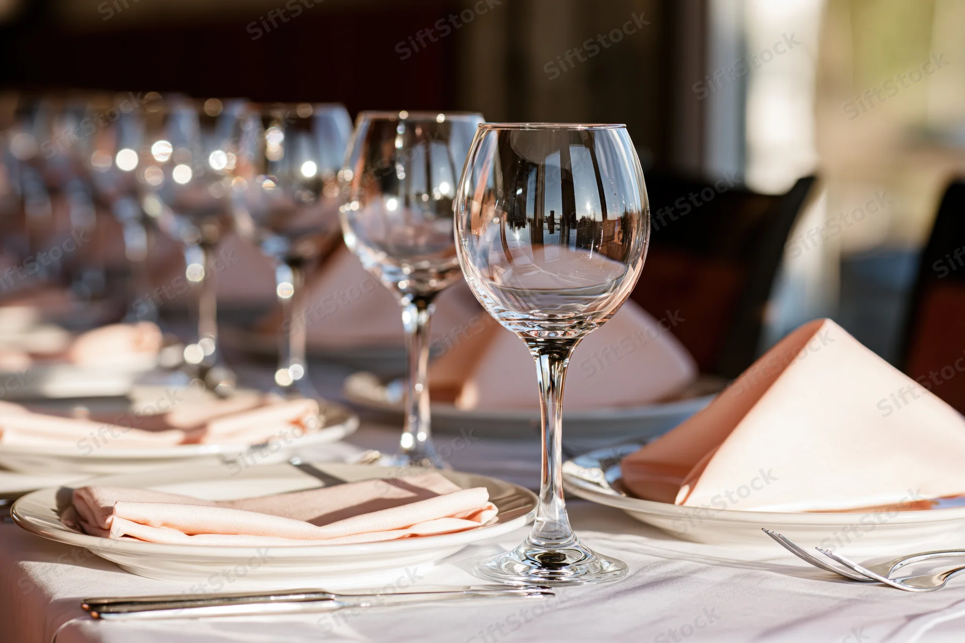 Formal dining table set with wine glasses and cutlery arranged in a row