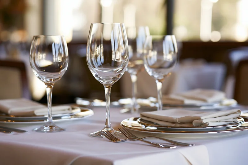 Formal dining table set with wine glasses, plates, and silverware in a restaurant interior