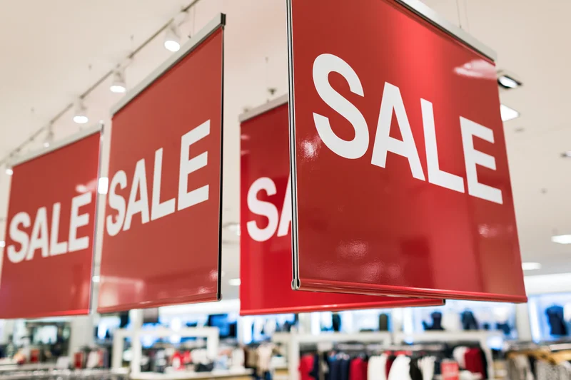 Red sale signs hanging from ceiling in retail store interior