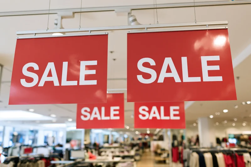 Red sale signs hanging from ceiling in a retail store interior