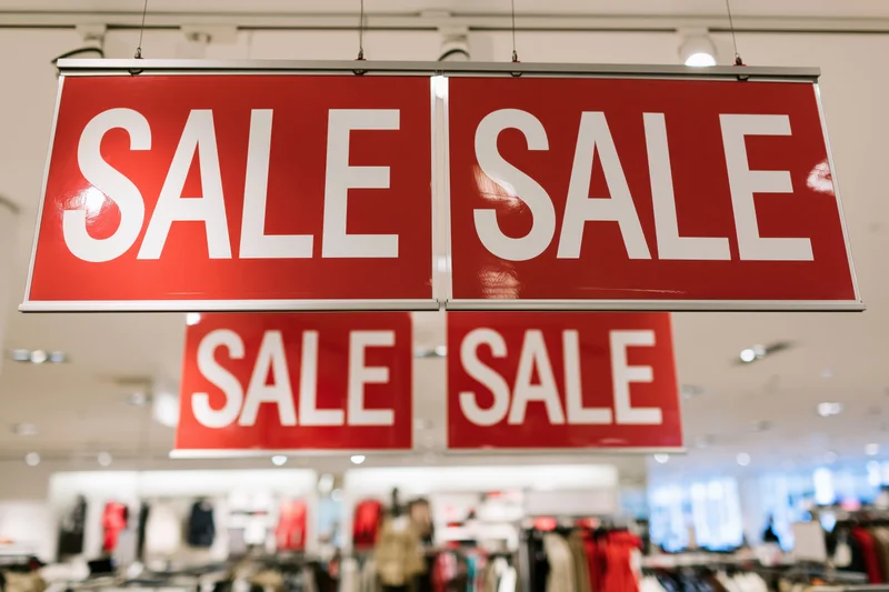 Red sale signs hanging from ceiling in retail store