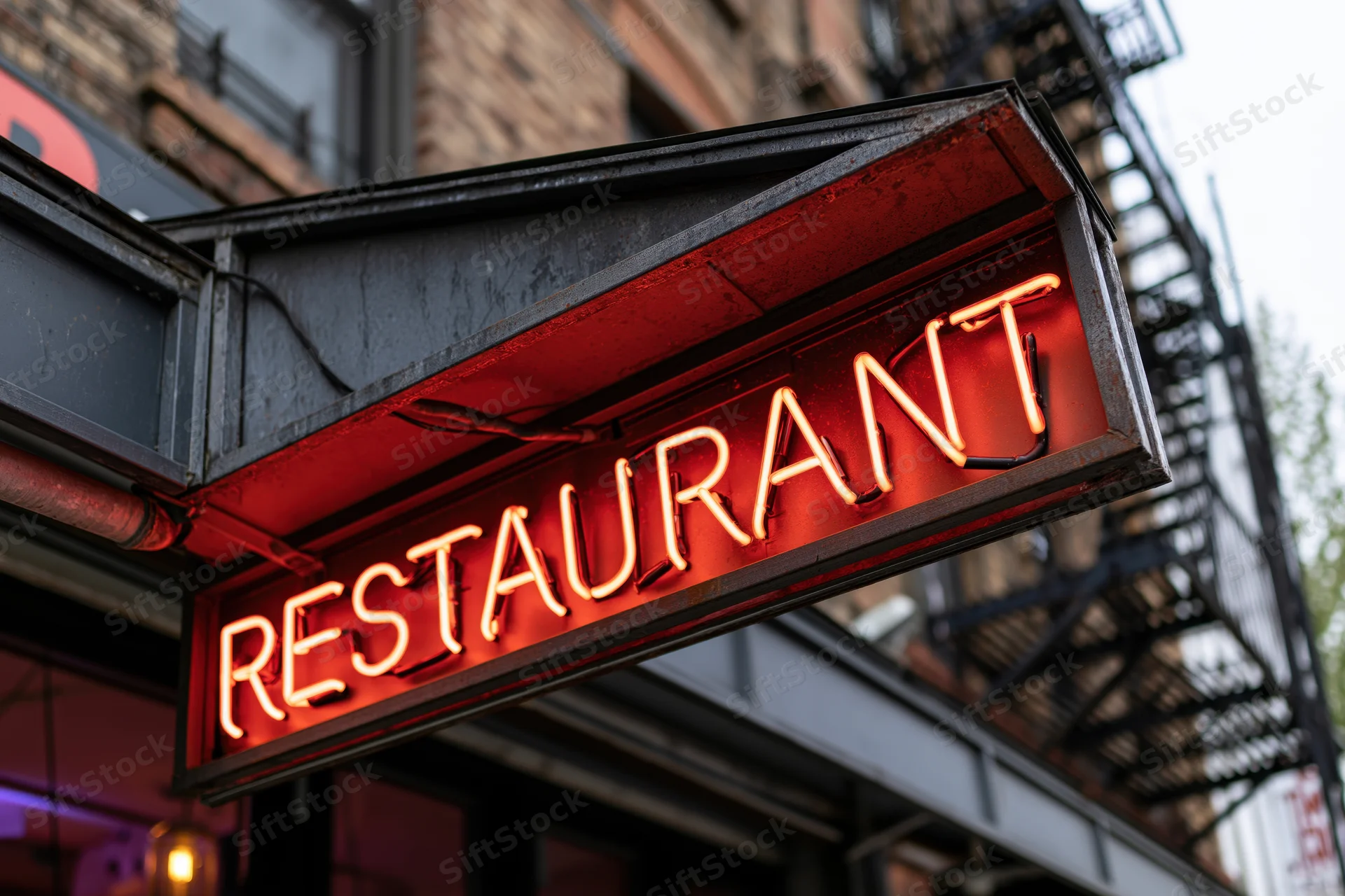 Glowing red-orange neon restaurant sign mounted on a dark metal frame outside a brick building