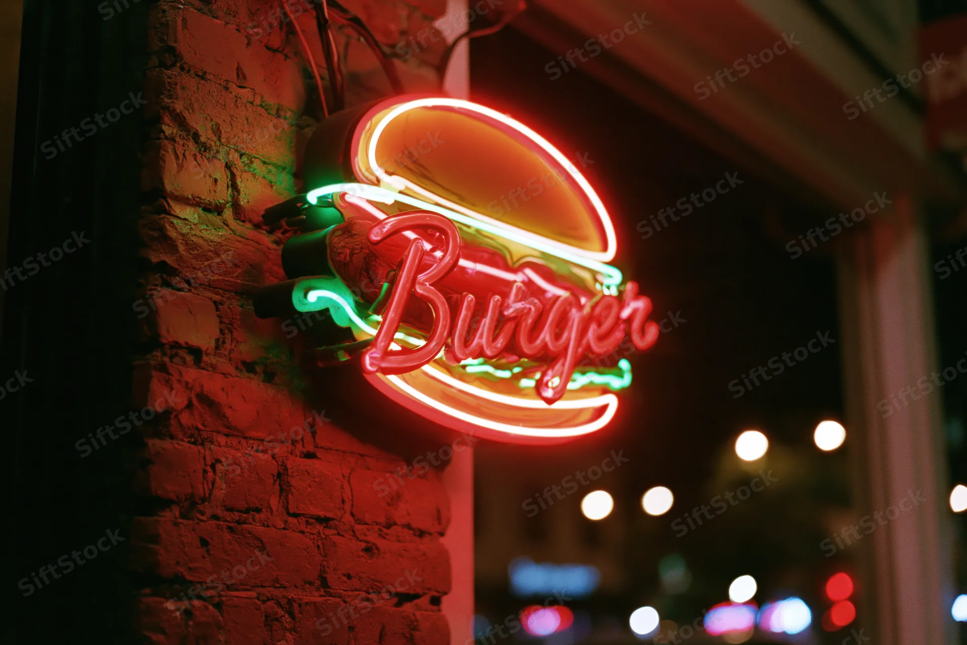 Glowing red neon burger sign mounted on a brick wall at night