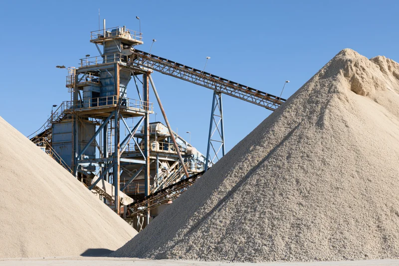 Gravel piles and conveyor machinery at an industrial quarry site