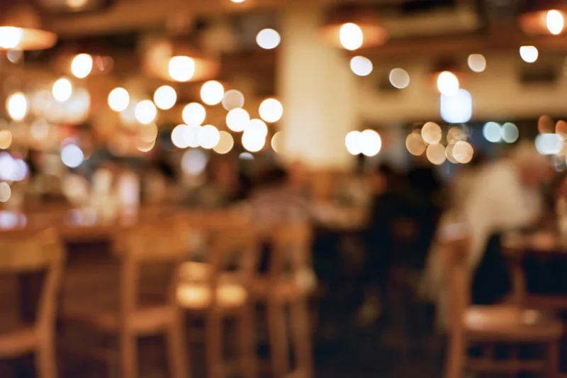 Blurred interior of a busy casual restaurant with warm lighting and wooden furniture