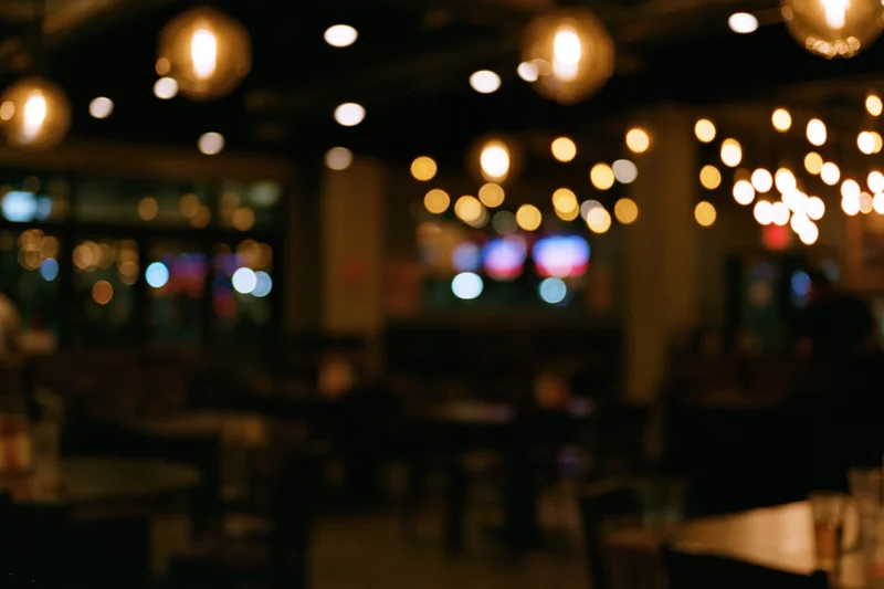 Blurred interior of empty restaurant at night with warm pendant lights glowing overhead
