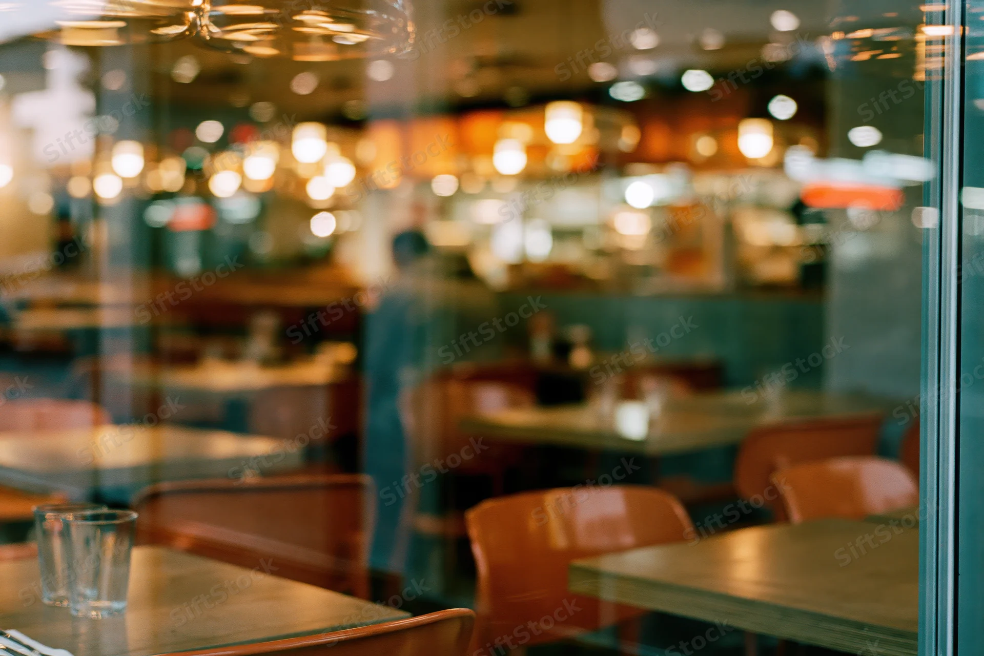 Casual restaurant interior viewed through glass window with wooden tables and chairs inside