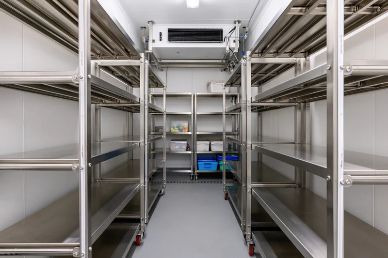Interior of a commercial walk-in refrigerator with stainless steel shelving and cooling unit