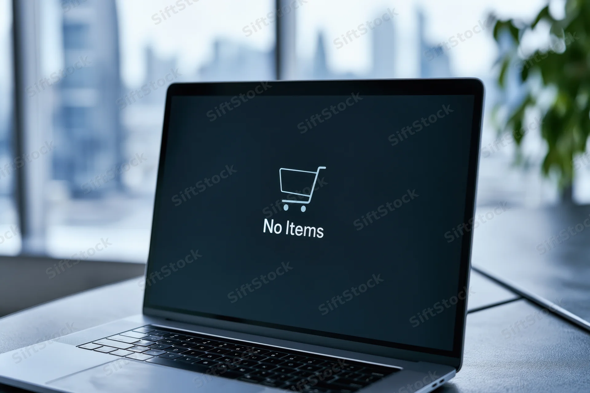Laptop showing empty shopping cart icon and no items text on dark screen on desk near window with city view