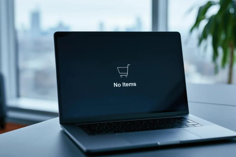 Laptop displaying empty shopping cart message on desk near window