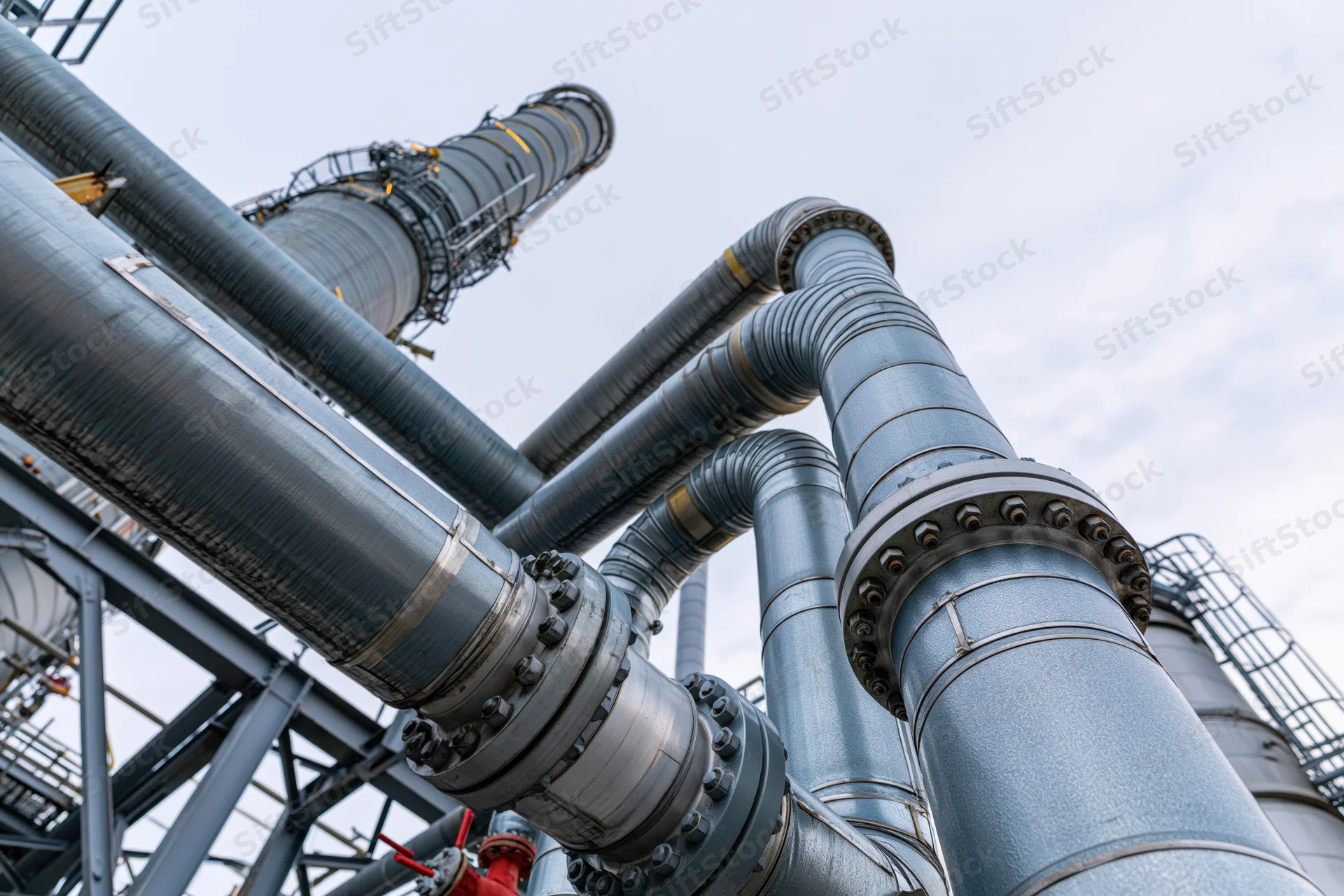 Large industrial pipeline network with flanged steel pipes and exhaust stacks at a petrochemical plant