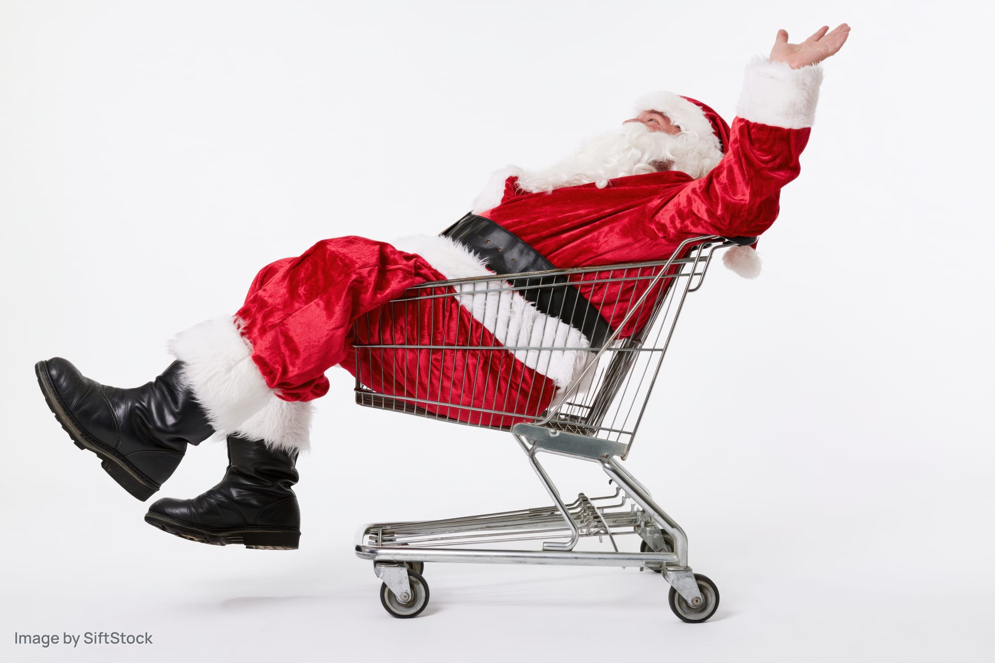 Santa reclining in a shopping cart with arms raised on white background