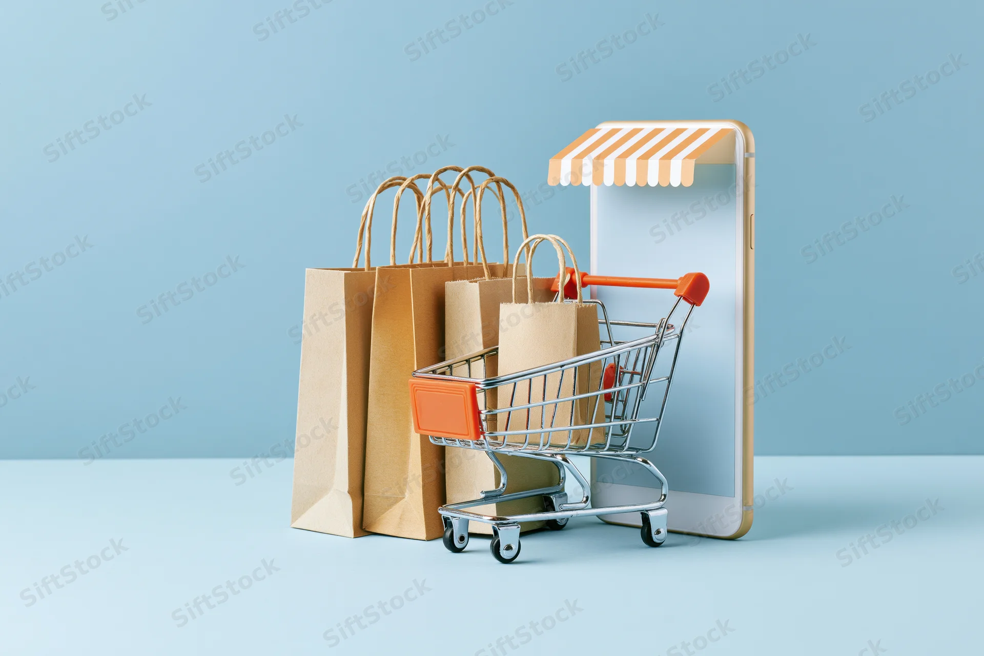 Smartphone with striped awning and miniature shopping cart beside paper bags on blue background