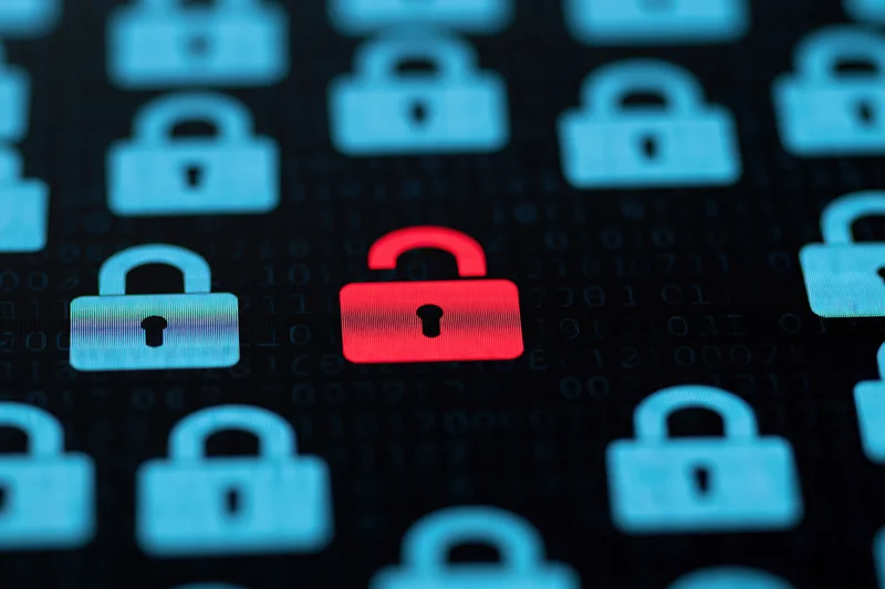 Red open padlock icon centered among blue closed padlocks on digital screen with binary code background