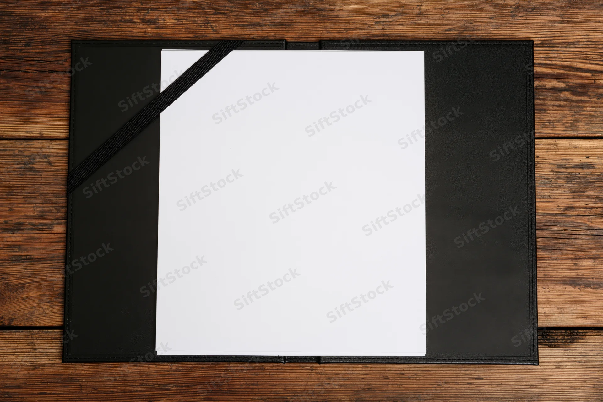 Open black leather restaurant check presenter with blank white paper on wooden table
