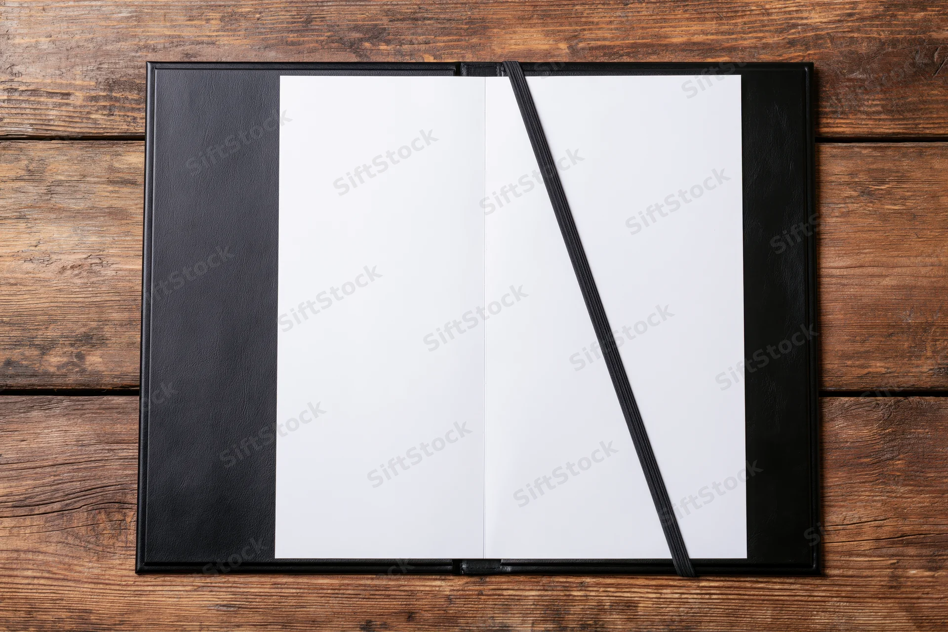 Open black leather restaurant menu presenter with blank white pages on wooden table