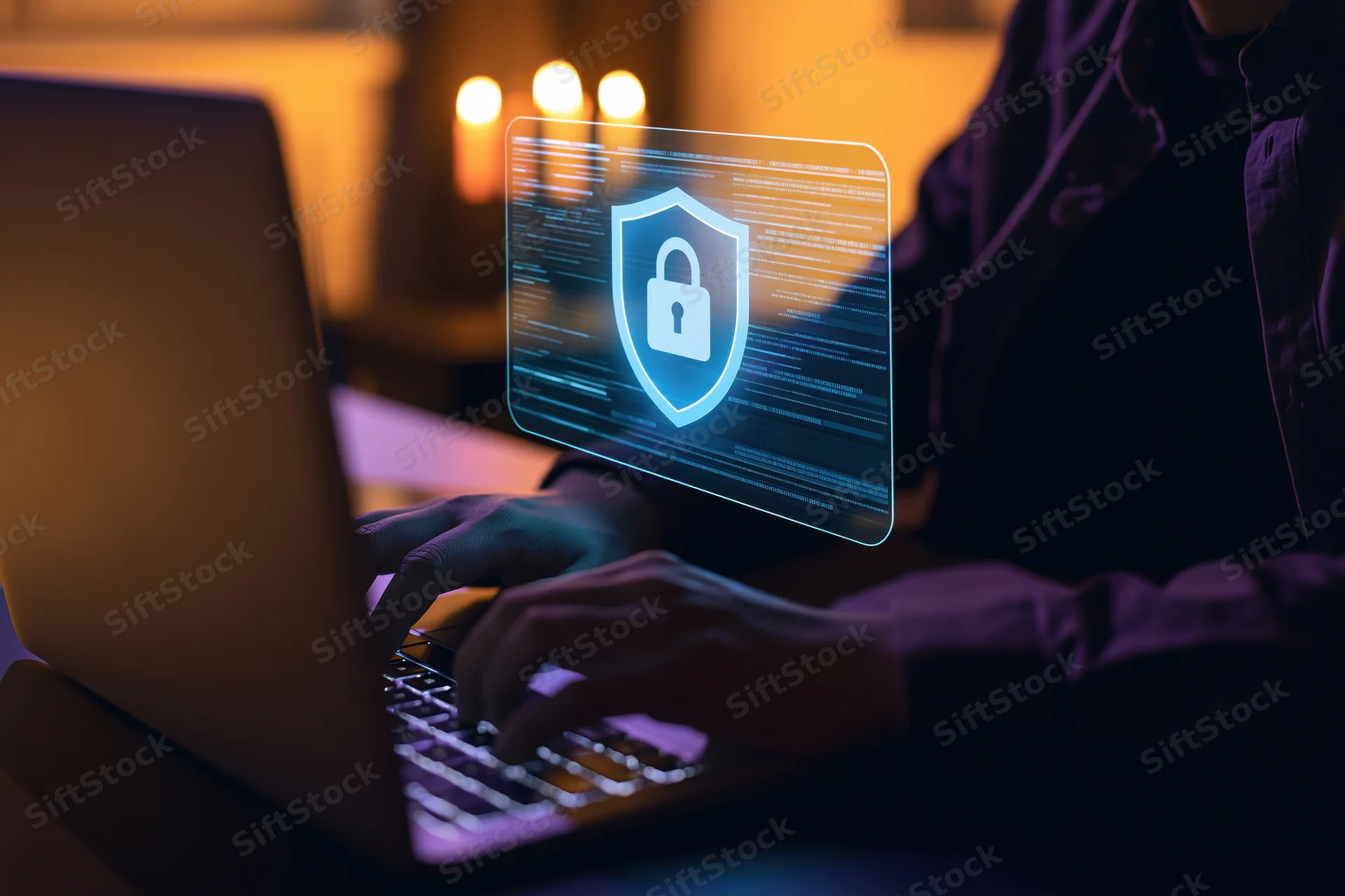 Person typing on laptop with holographic security shield in dark room