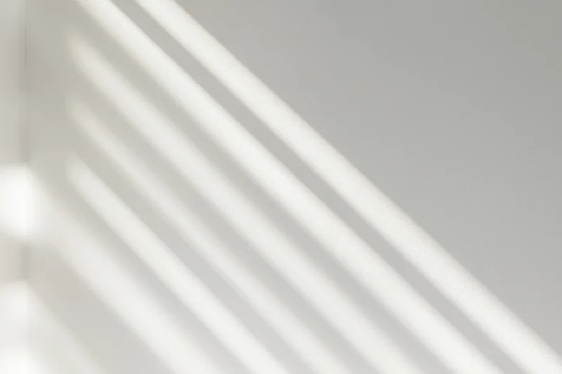 Diagonal light and shadow stripes on a white wall surface in a bright interior