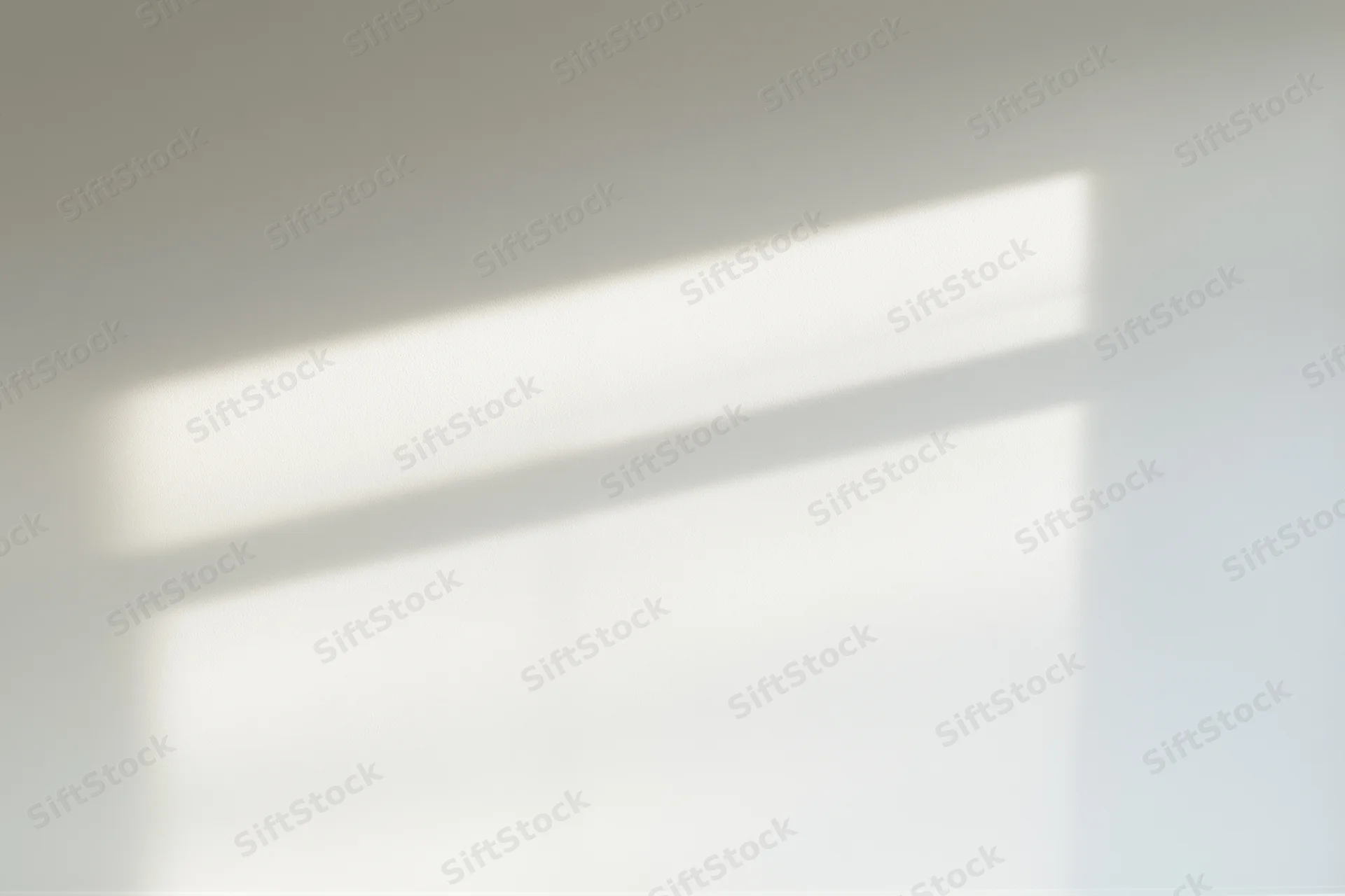 Rectangular beam of bright afternoon sunlight on a plain white interior wall