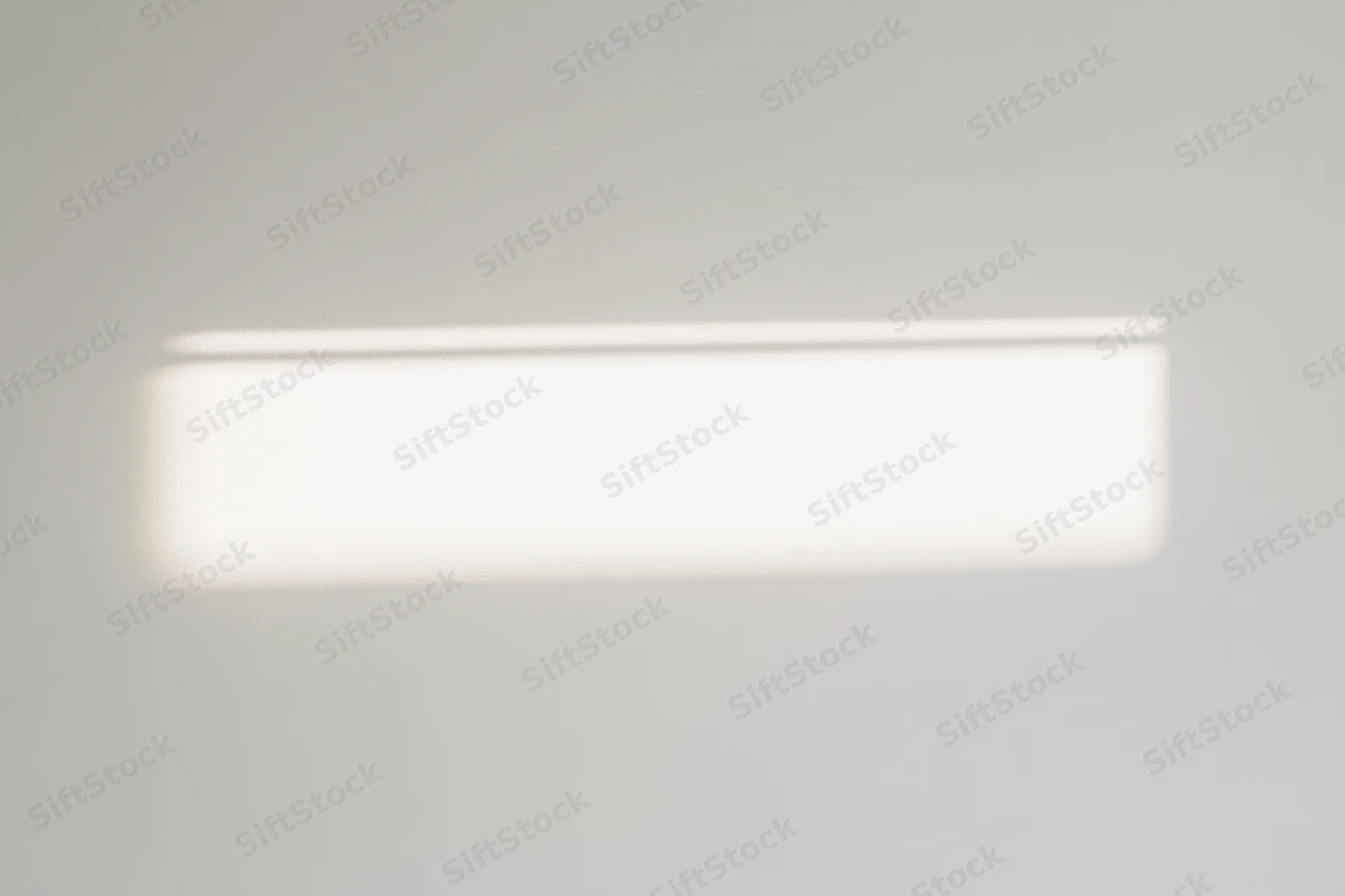 Bright rectangular patch of sunlight on a white ceiling indoors