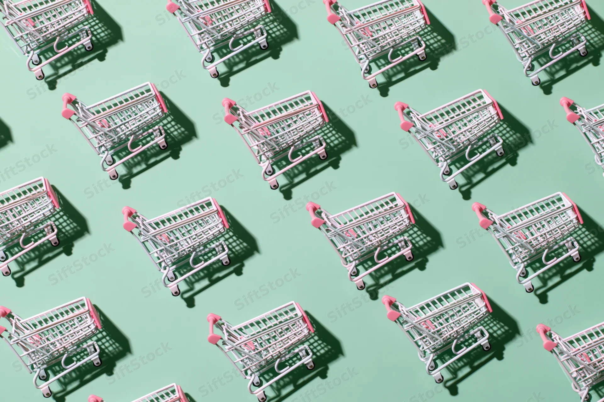 Repeating pattern of miniature pink and silver shopping carts on a mint green background