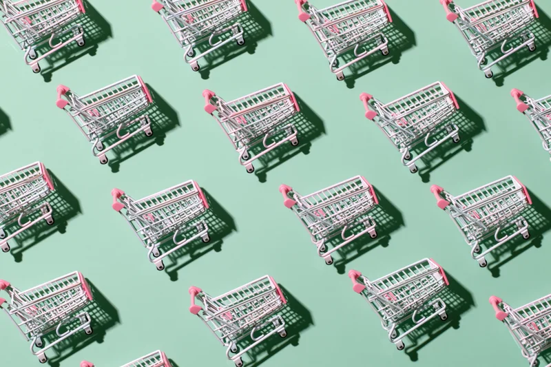 Repeating pattern of miniature pink and silver shopping carts on a mint green background