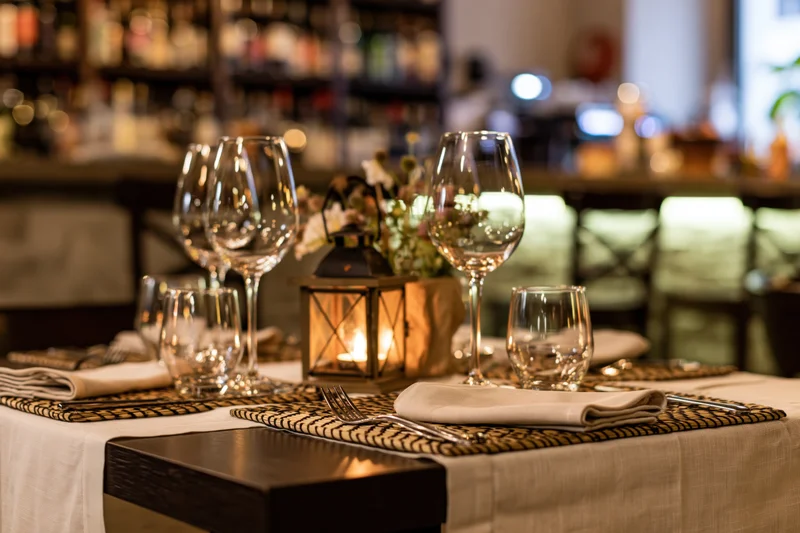 Dining table set for service with empty wine glasses and candlelit lantern in restaurant interior