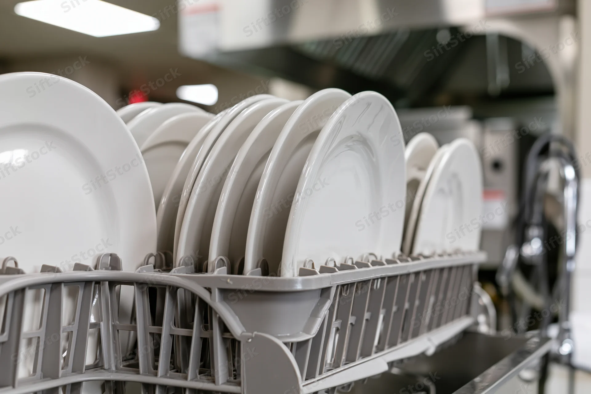 Clean white ceramic plates standing upright in a dish rack in a commercial kitchen