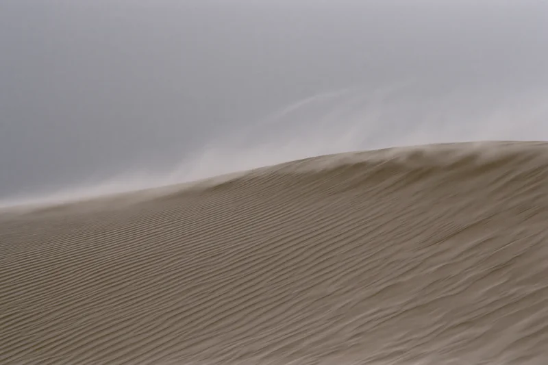 Sand blowing off the crest of a desert dune during a windstorm