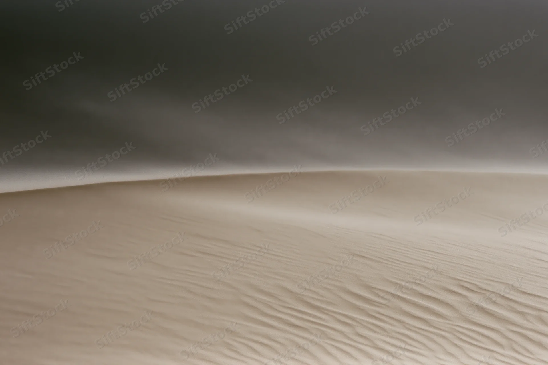 Sand blowing off the crest of a desert dune during a windstorm