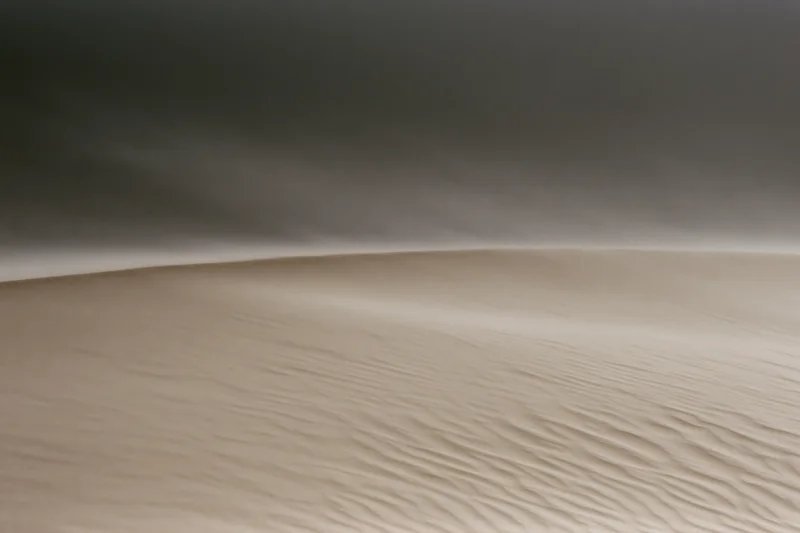 Sand blowing off the crest of a desert dune during a windstorm