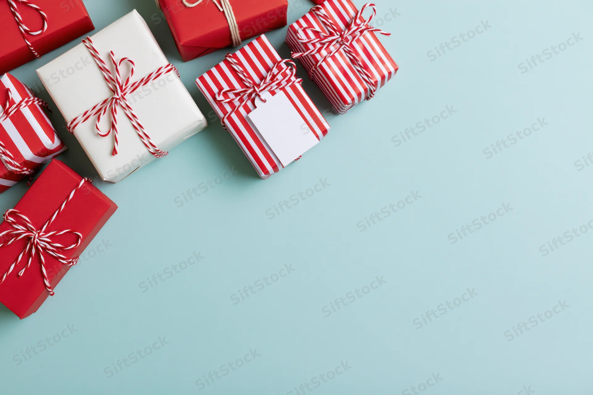 Wrapped gift boxes arranged along the left edge of a light blue surface with copyspace