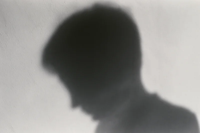 Shadow of a person looking downward cast on a pale concrete wall