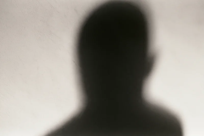 Shadow of a person looking downward cast on a pale concrete wall