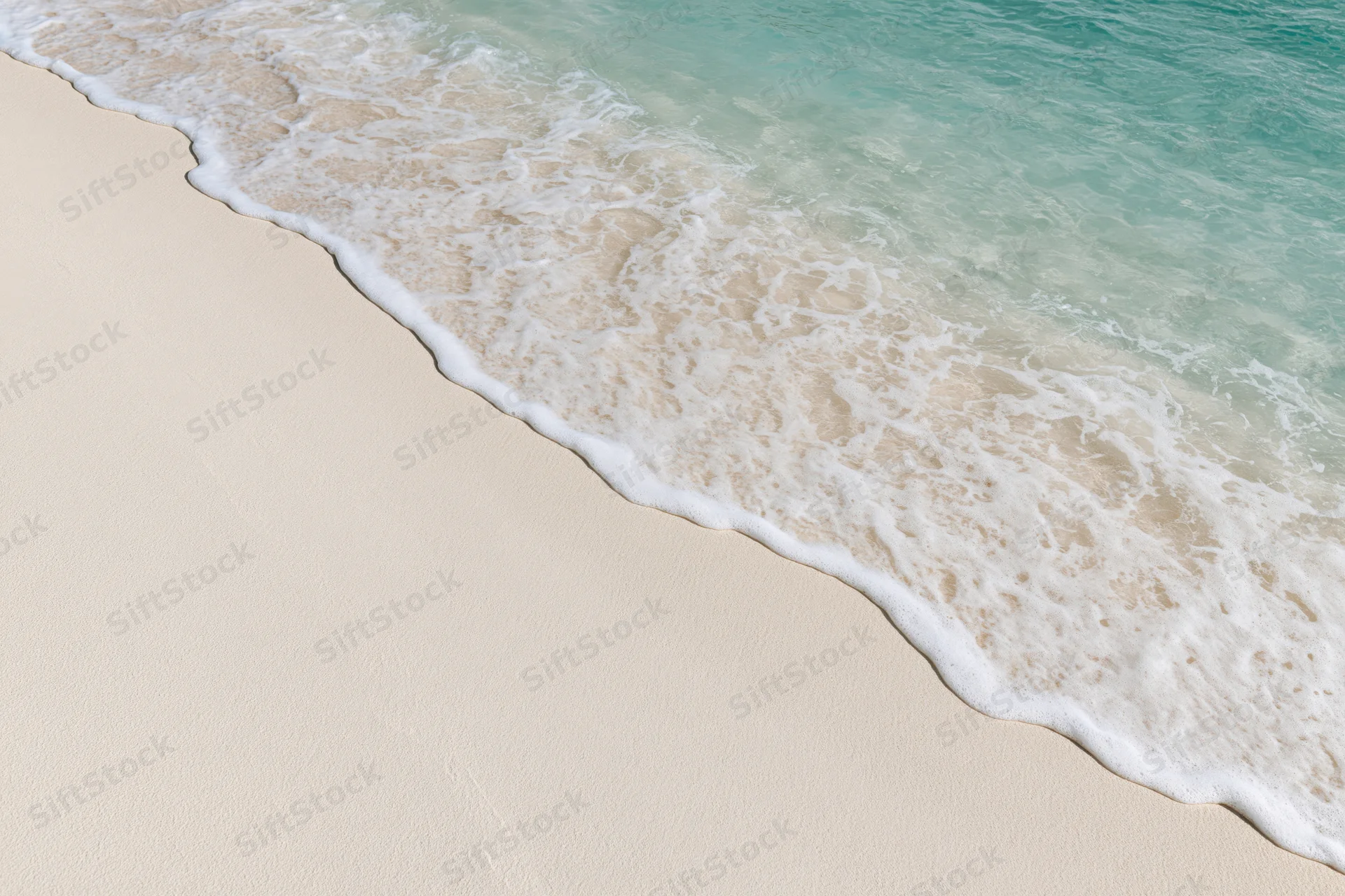 Shallow ocean wave gently washing over fine white sand at the beach