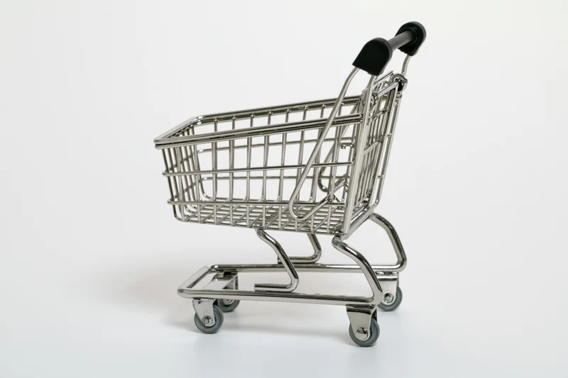 Miniature chrome shopping cart replica on white background