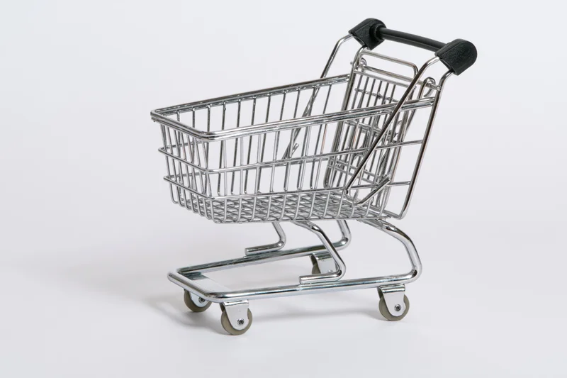 Miniature chrome shopping cart replica viewed from the side on white background