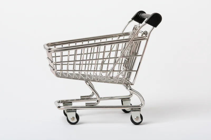 Miniature chrome shopping cart replica viewed from the side on a white background