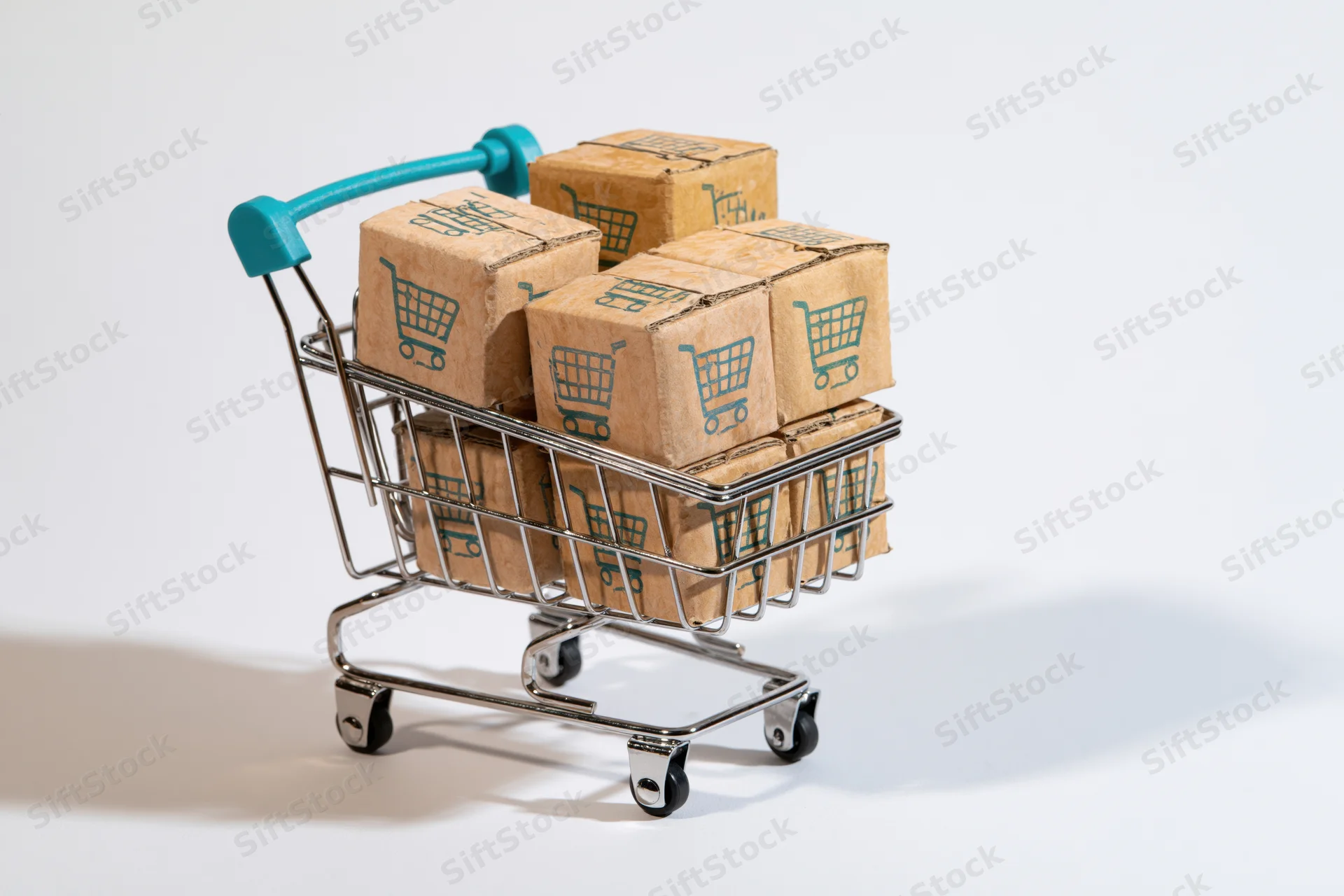 Miniature shopping cart filled with cardboard boxes printed with shopping cart symbols on white background
